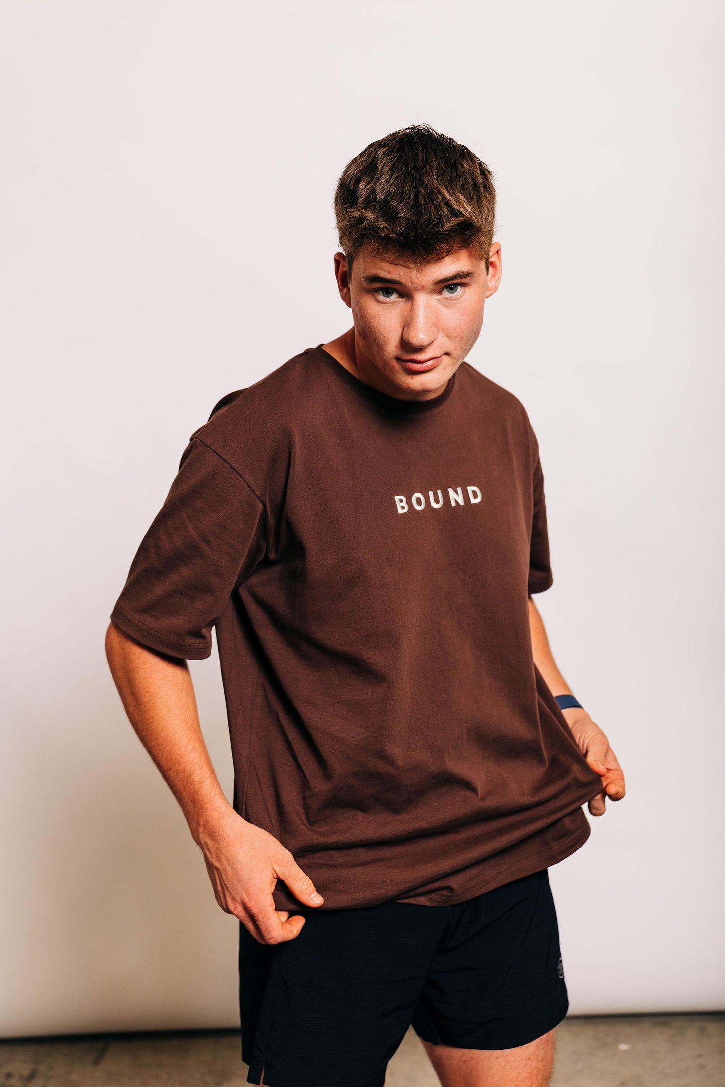 Man in The Off-Day Tee tugging the hem to show length and fit