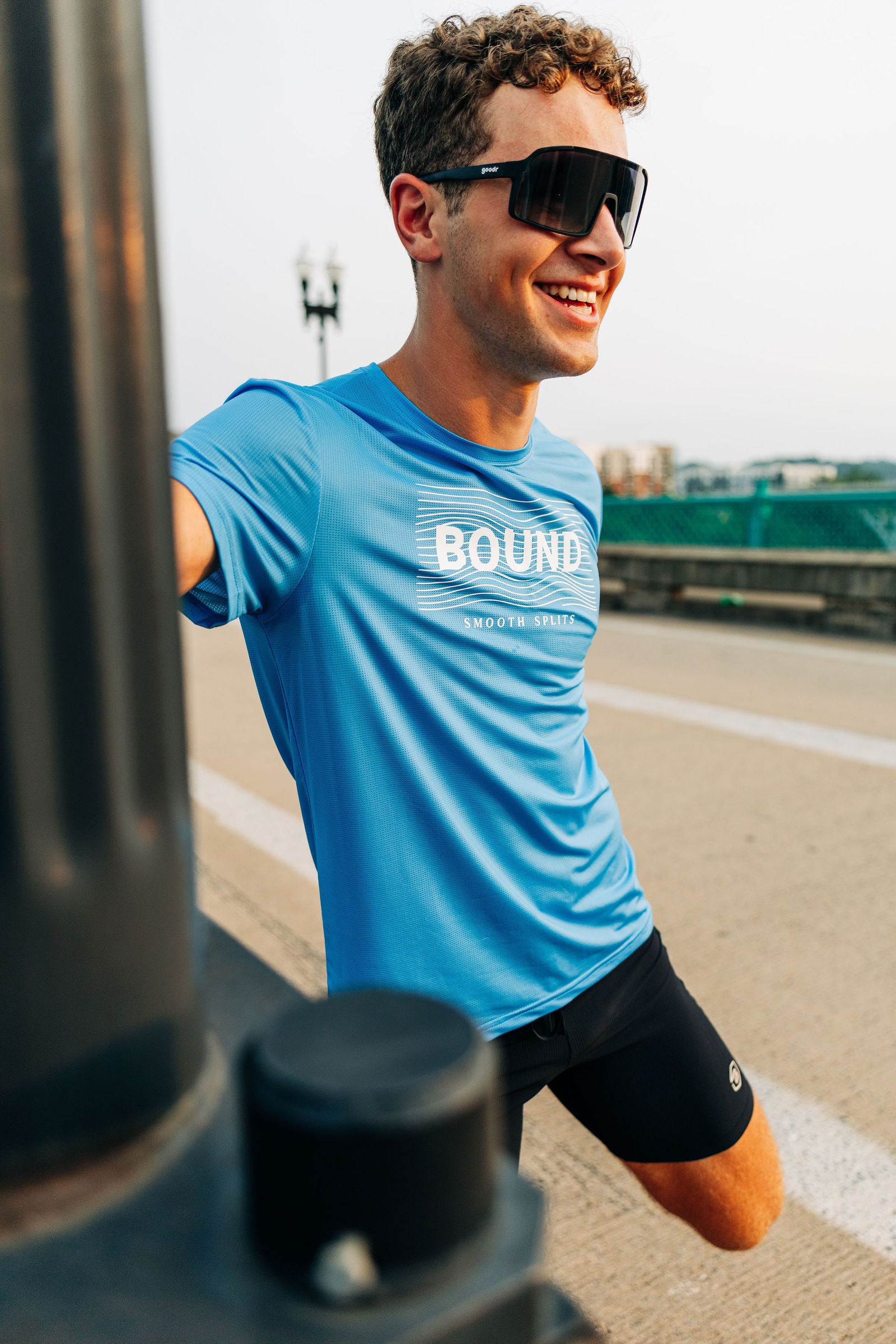 Runner in the Smooth Splits Short Sleeve stretching on a bridge