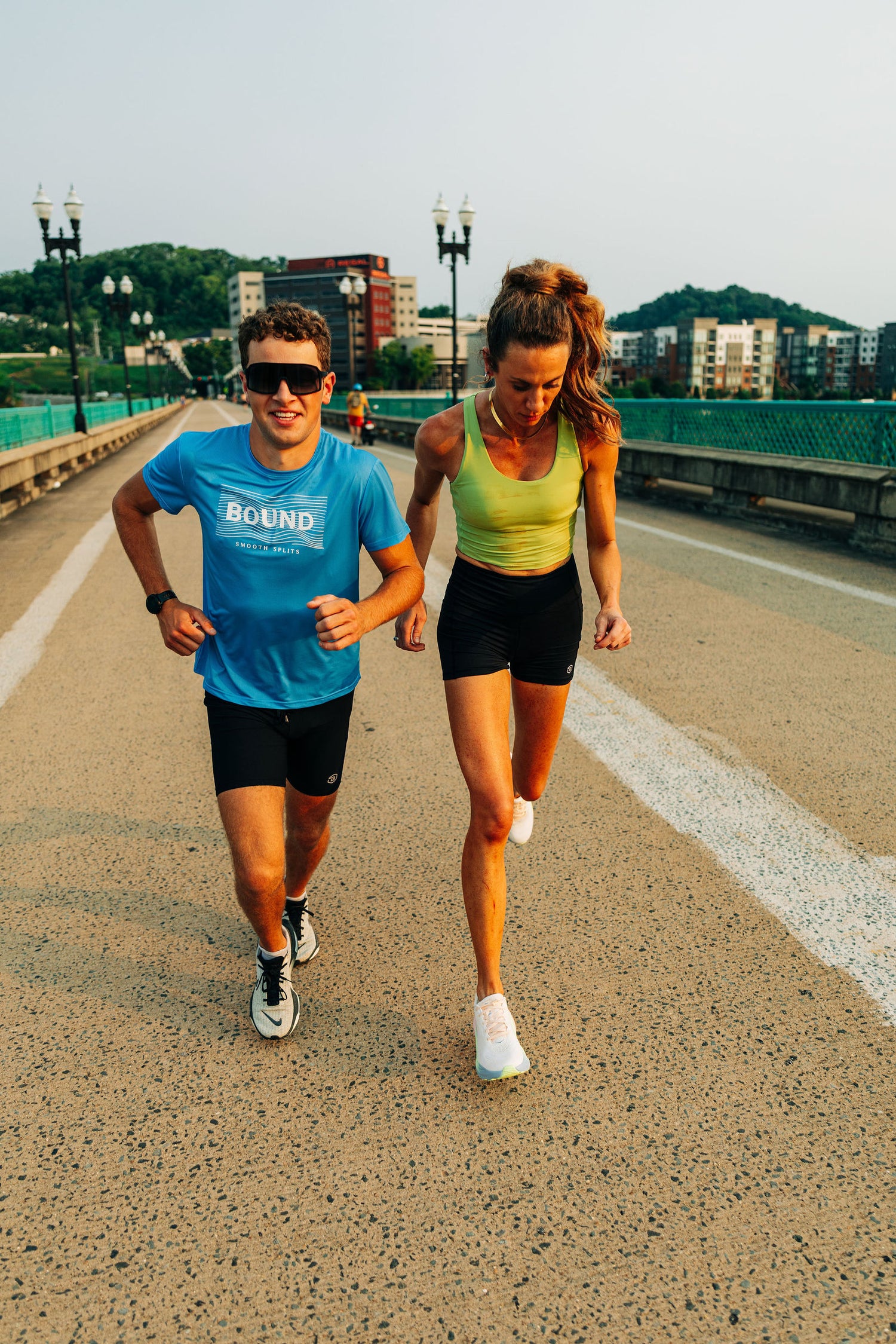 Two runners in BOUND gear running side by side across an Indianapolis bridge