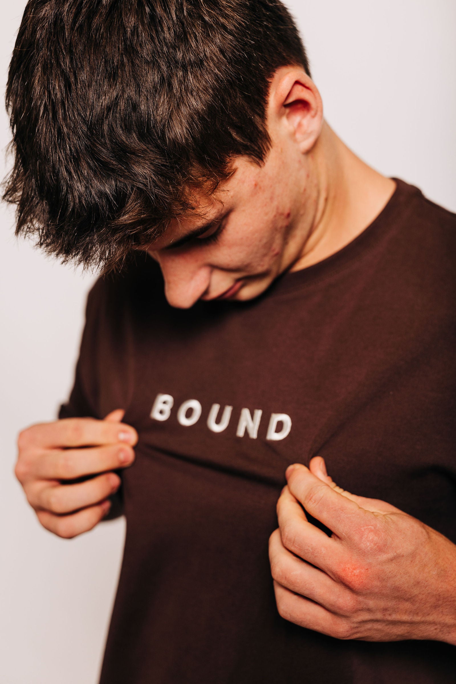 Hands holding the heavyweight cotton of The Off-Day Tee by the BOUND print