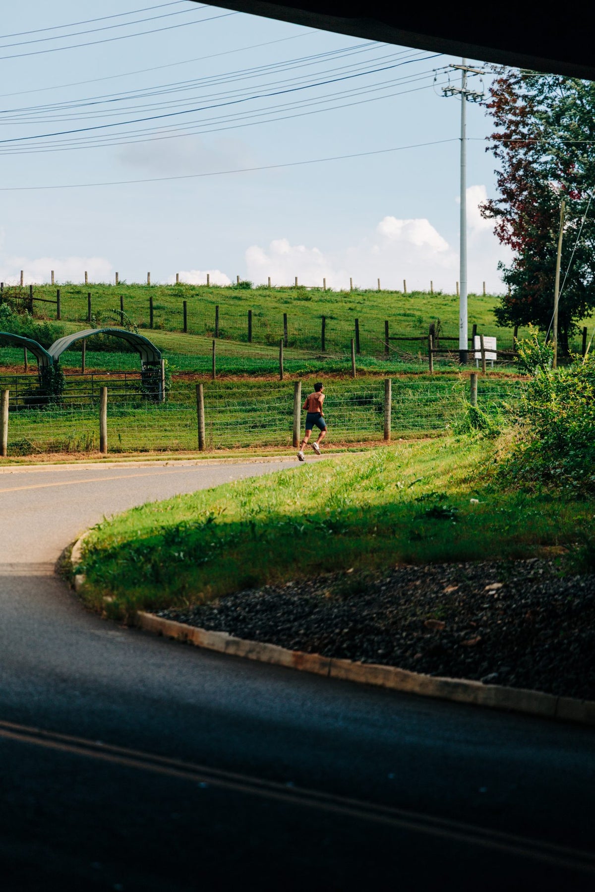 A runner rounding a curve on a green hillside path