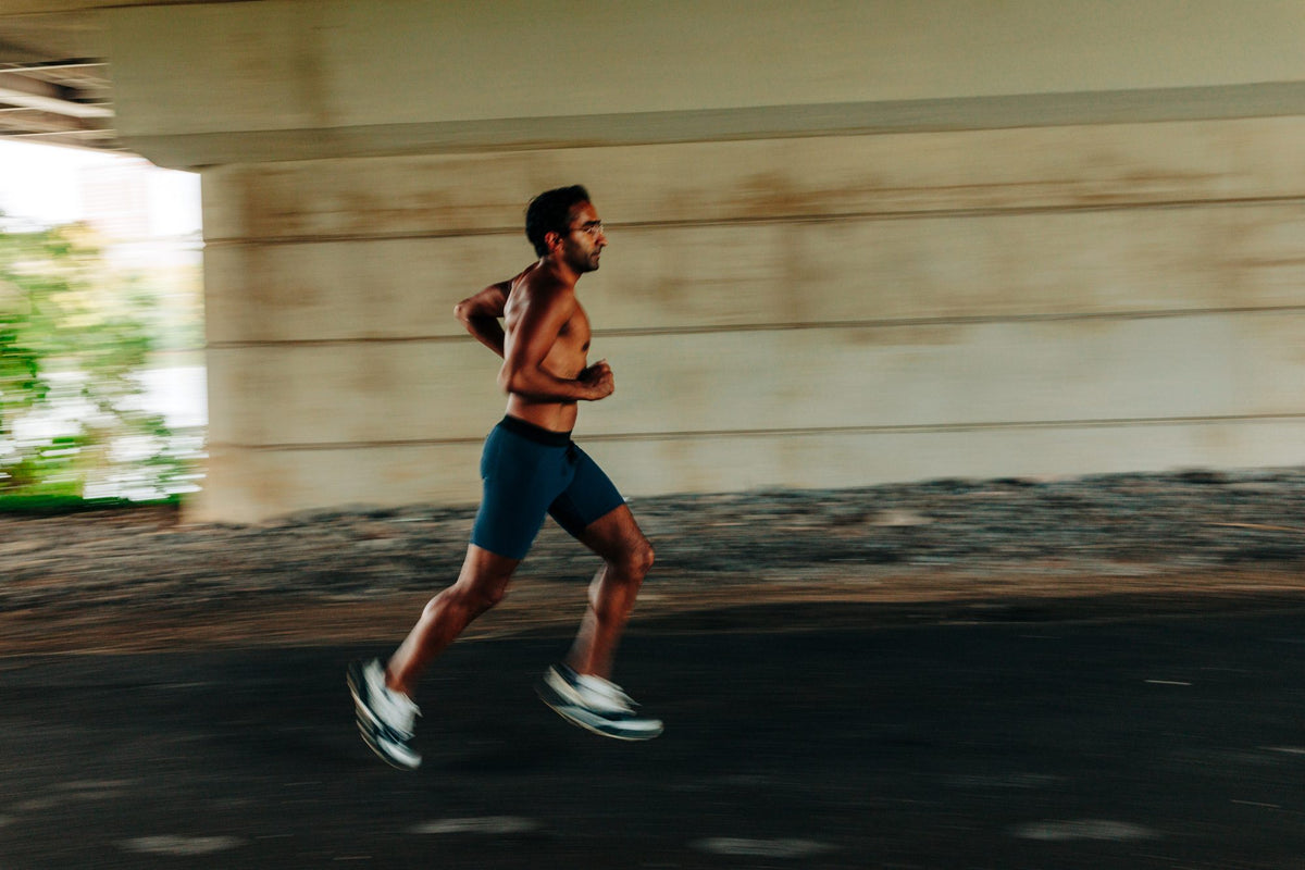 A runner mid-stride under a bridge